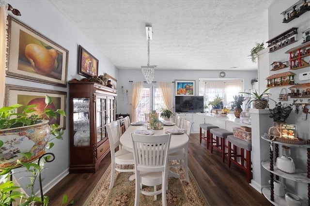 dining area with a chandelier, dark wood finished floors, and a textured ceiling