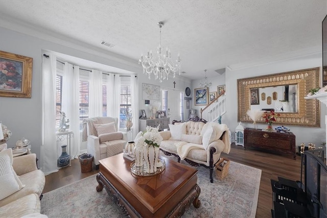 living area featuring a textured ceiling, dark wood-type flooring, visible vents, and a notable chandelier