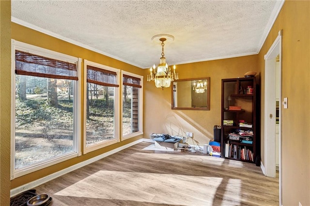 dining space with crown molding, hardwood / wood-style floors, a textured ceiling, and a chandelier