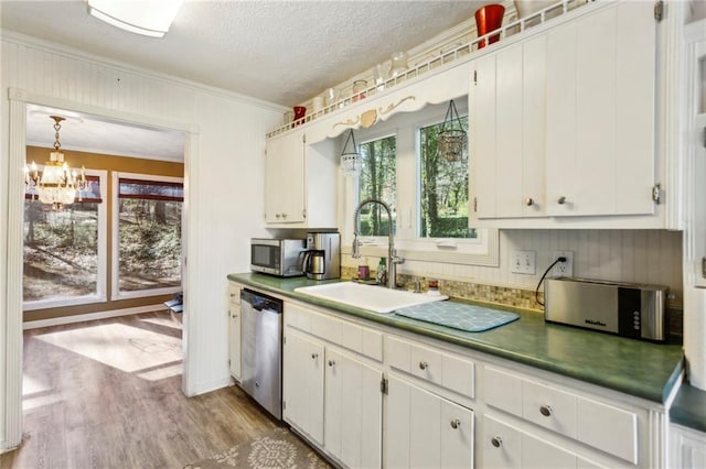 kitchen with white cabinetry, stainless steel appliances, decorative light fixtures, and sink