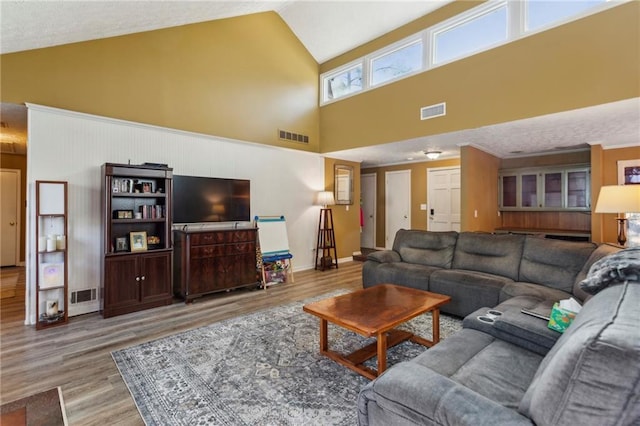 living room featuring high vaulted ceiling and light hardwood / wood-style floors