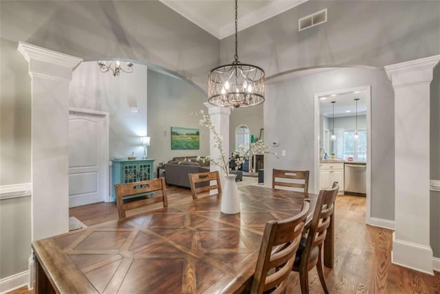 dining space with an inviting chandelier, decorative columns, and light hardwood / wood-style flooring