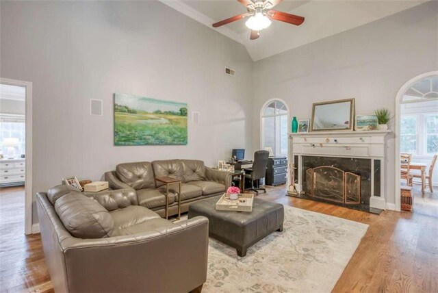 living room with ceiling fan, light hardwood / wood-style floors, a wealth of natural light, and a premium fireplace