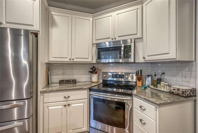 kitchen featuring dark stone countertops, appliances with stainless steel finishes, white cabinetry, and tasteful backsplash