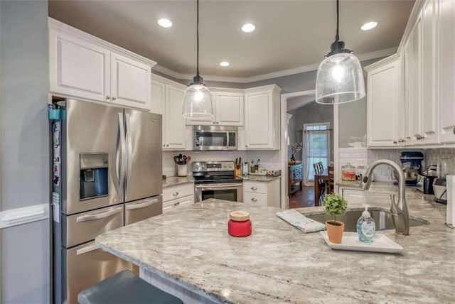 kitchen with hanging light fixtures, tasteful backsplash, stainless steel appliances, and white cabinetry