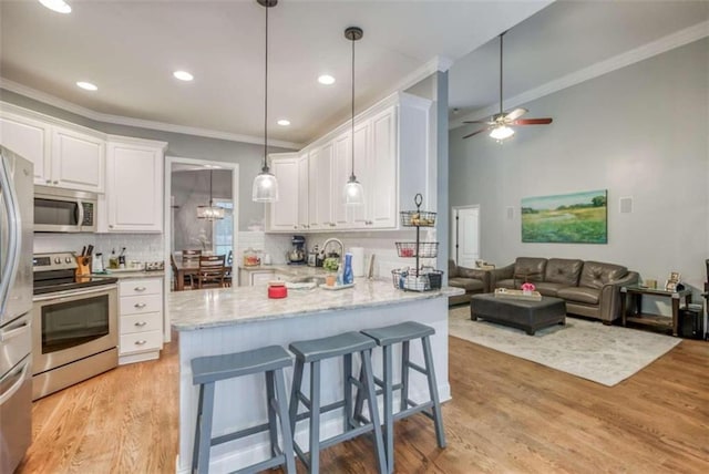 kitchen featuring ceiling fan, appliances with stainless steel finishes, light hardwood / wood-style floors, tasteful backsplash, and white cabinetry