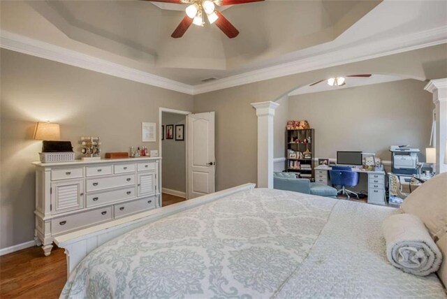 bedroom featuring ceiling fan, a raised ceiling, hardwood / wood-style floors, ornamental molding, and decorative columns