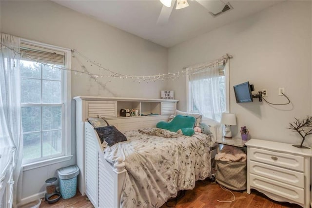 bedroom with ceiling fan, dark wood-type flooring, and multiple windows