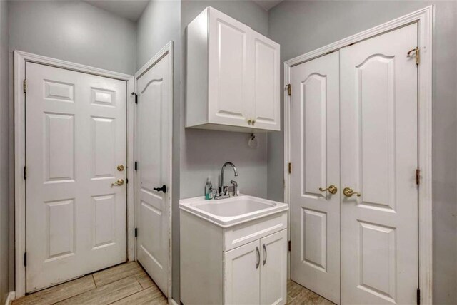 laundry area featuring sink and light hardwood / wood-style floors