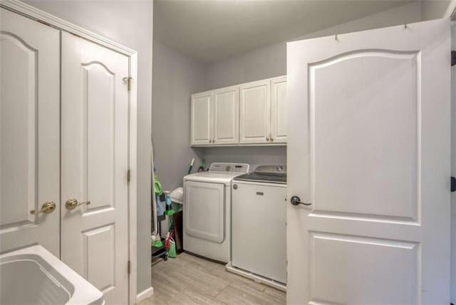 clothes washing area featuring cabinets, washer and dryer, and light tile floors