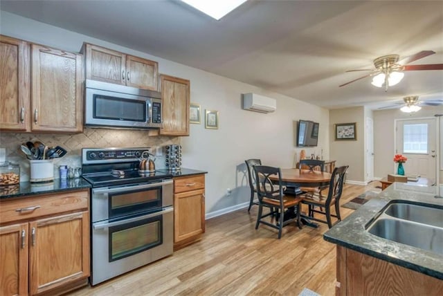 kitchen with ceiling fan, tasteful backsplash, appliances with stainless steel finishes, light wood-type flooring, and a wall unit AC