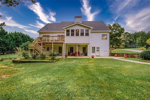 back of property featuring a wooden deck, a yard, and a patio