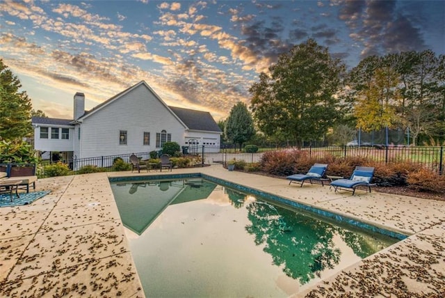 pool at dusk featuring a patio