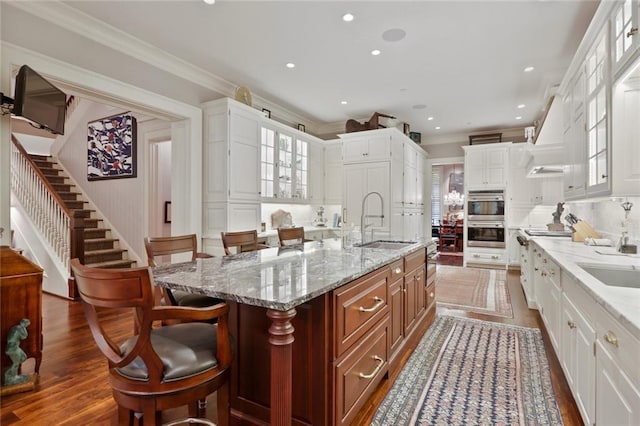 kitchen featuring stainless steel appliances, a kitchen breakfast bar, sink, white cabinetry, and a center island with sink