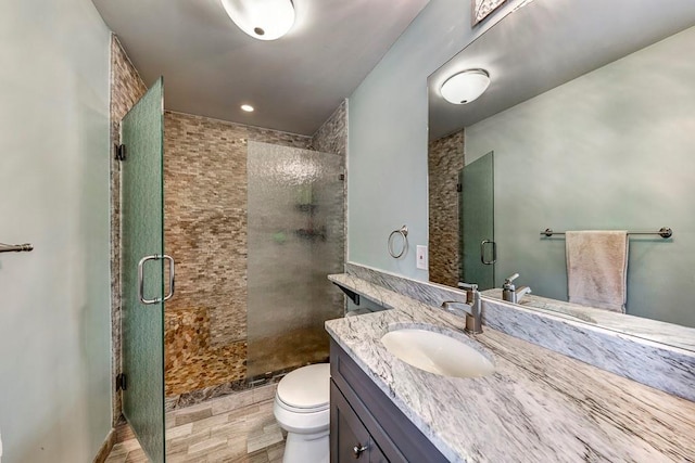 bathroom with toilet, a shower with shower door, and large vanity