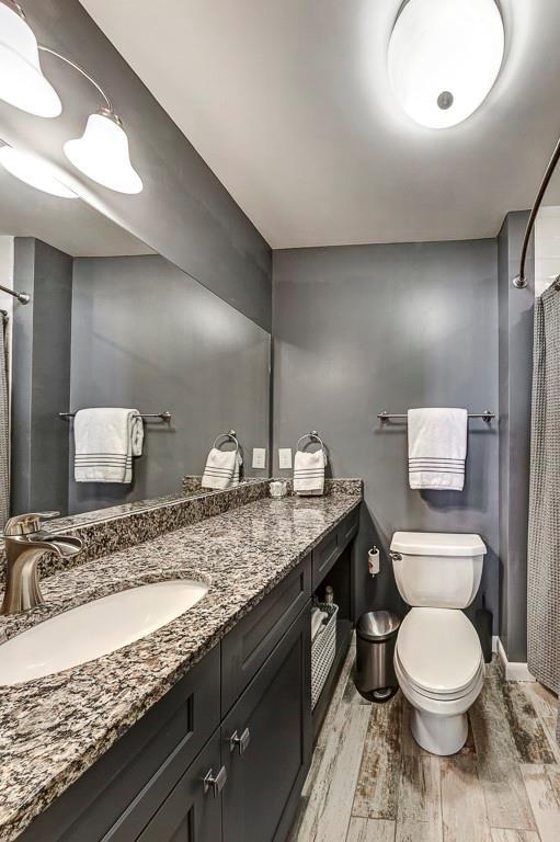 bathroom with toilet, vanity, and hardwood / wood-style flooring