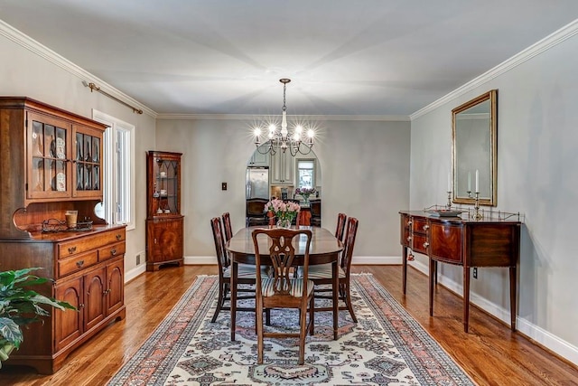 dining space featuring a notable chandelier, light hardwood / wood-style flooring, and ornamental molding