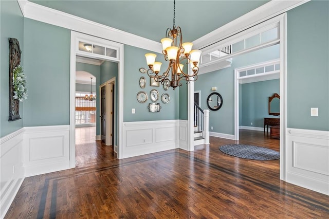 interior space featuring a notable chandelier, ornamental molding, and dark wood-type flooring