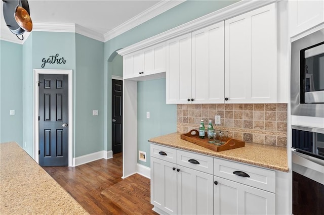 kitchen with dark hardwood / wood-style flooring, backsplash, white cabinetry, and stainless steel appliances