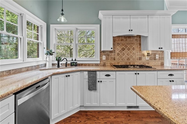 kitchen with dark wood-type flooring, white cabinets, pendant lighting, stainless steel appliances, and light stone countertops