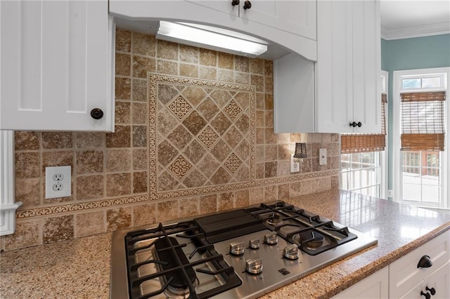 kitchen with white cabinets, backsplash, stainless steel gas stovetop, and light stone counters