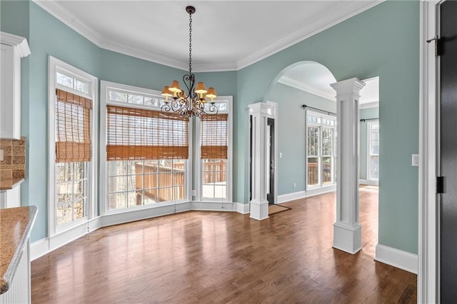 unfurnished dining area with a chandelier, ornamental molding, dark hardwood / wood-style floors, and decorative columns