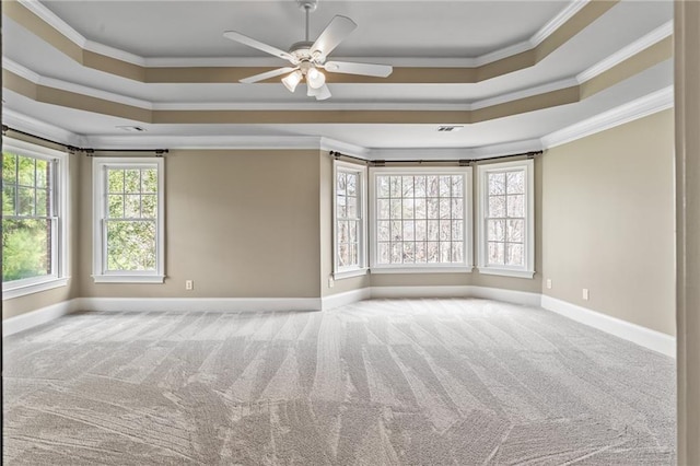 carpeted empty room featuring a raised ceiling, ornamental molding, and ceiling fan