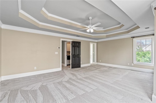 spare room with ceiling fan, crown molding, a tray ceiling, and light carpet