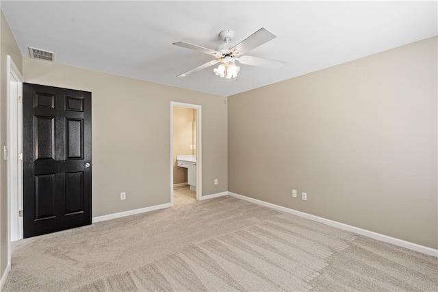 unfurnished bedroom with ceiling fan, ensuite bathroom, and light colored carpet