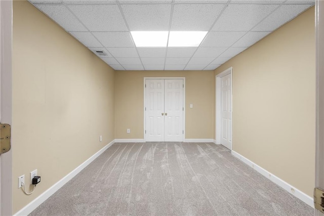 empty room featuring a drop ceiling and light carpet