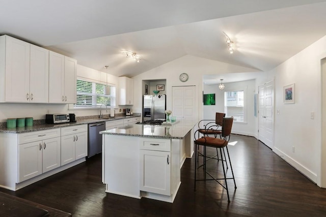 kitchen featuring a kitchen breakfast bar, dark wood-type flooring, appliances with stainless steel finishes, white cabinets, and track lighting