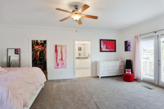 carpeted bedroom featuring a closet, a walk in closet, ceiling fan, ensuite bath, and ornamental molding