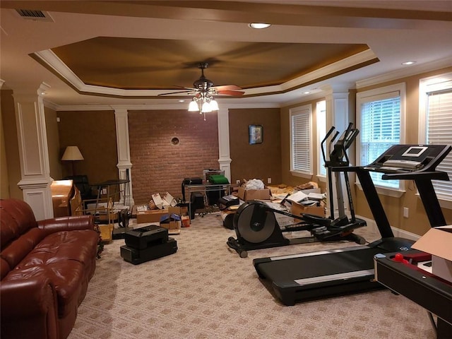 workout room featuring ceiling fan, decorative columns, crown molding, light carpet, and a tray ceiling