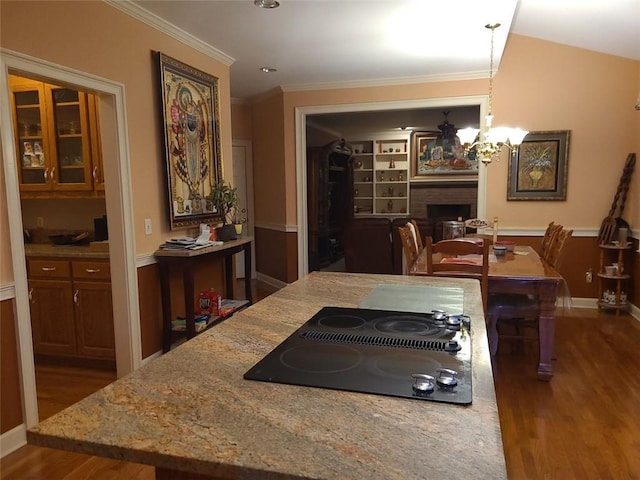 kitchen featuring dark wood-type flooring, black electric stovetop, decorative light fixtures, a chandelier, and light stone countertops