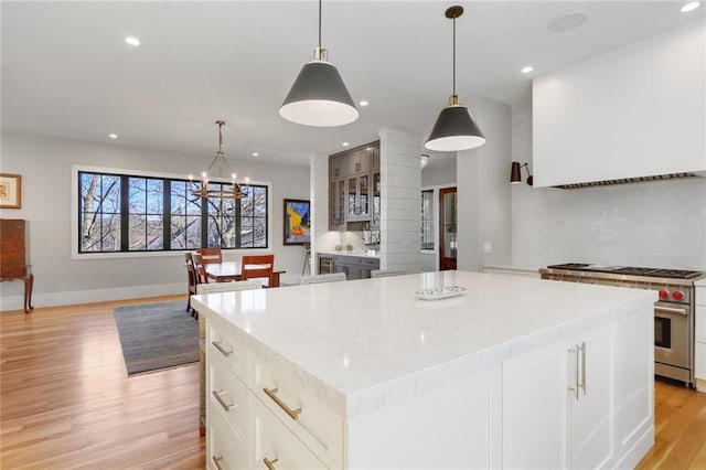 1068 Amsterdam Avenue Ne, Atlanta, GA 30306 - kitchen featuring light hardwood / wood-style floors, a center island, a notable chandelier, backsplash, and designer stove