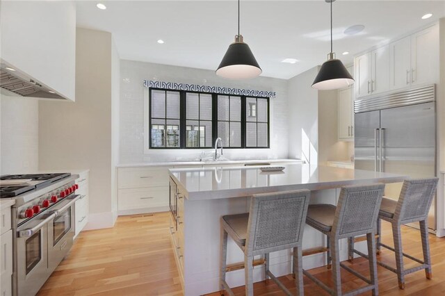 1068 Amsterdam Avenue Ne, Atlanta, GA 30306 - kitchen with high quality appliances, white cabinetry, light hardwood / wood-style floors, a center island, and pendant lighting