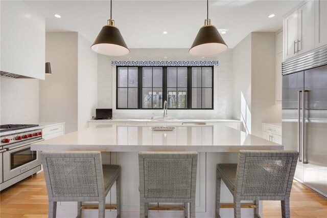 1068 Amsterdam Avenue Ne, Atlanta, GA 30306 - kitchen with white cabinets, a kitchen bar, high end appliances, and light wood-type flooring