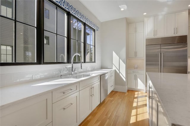 1068 Amsterdam Avenue Ne, Atlanta, GA 30306 - kitchen with appliances with stainless steel finishes, light wood-type flooring, sink, light stone countertops, and white cabinets