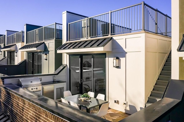 rear view of property featuring a balcony, an outdoor kitchen, and sink