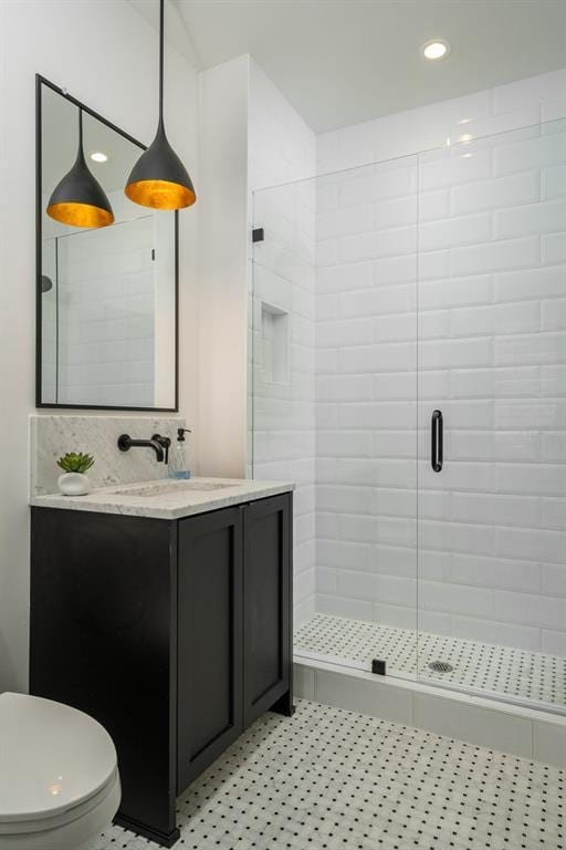 bathroom featuring toilet, vanity with extensive cabinet space, tile flooring, and an enclosed shower