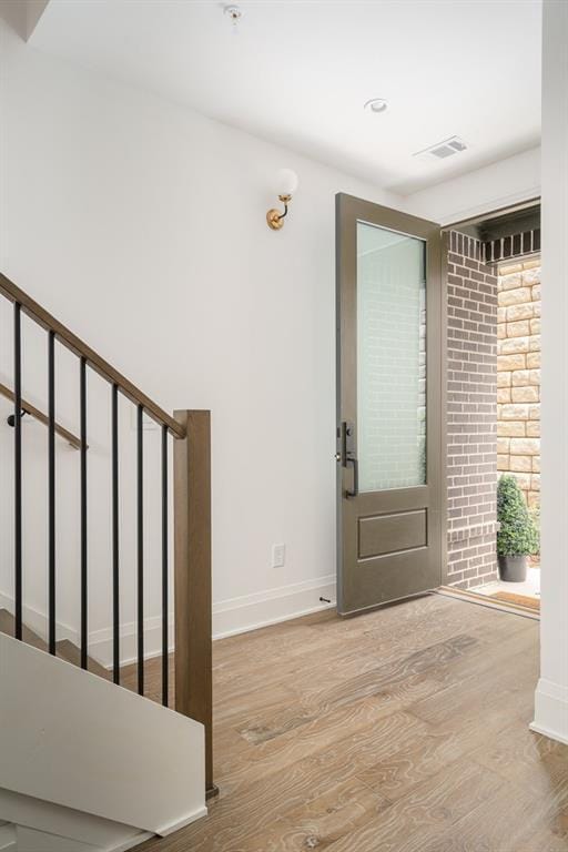 foyer with brick wall and light hardwood / wood-style floors