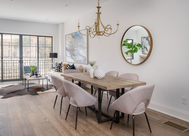 dining room with light hardwood / wood-style flooring and a notable chandelier