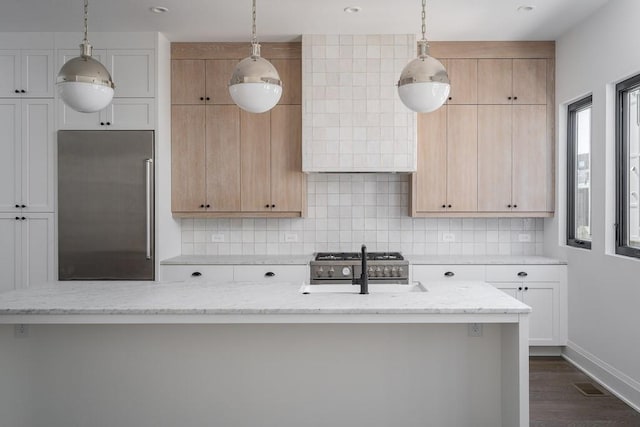 kitchen featuring dark wood-type flooring, tasteful backsplash, white cabinetry, premium appliances, and light stone countertops