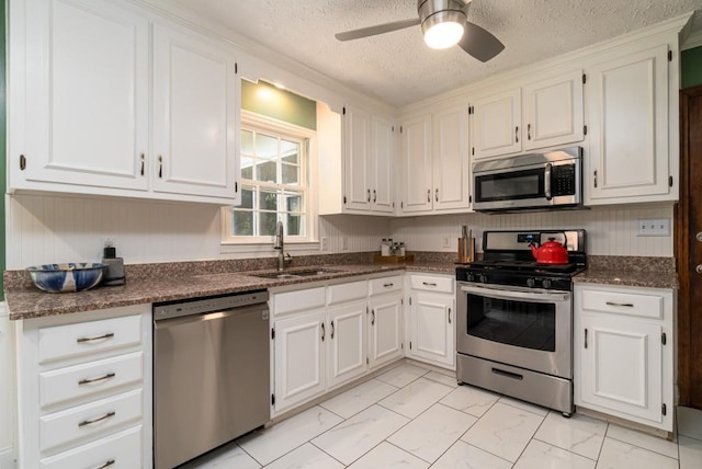 kitchen with light tile floors, appliances with stainless steel finishes, white cabinetry, and ceiling fan