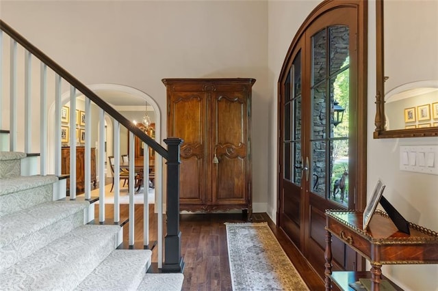 foyer with french doors, a notable chandelier, dark wood-type flooring, and ornamental molding