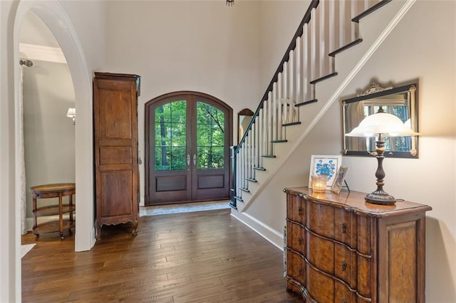 foyer entrance featuring french doors, dark wood-type flooring, and a towering ceiling