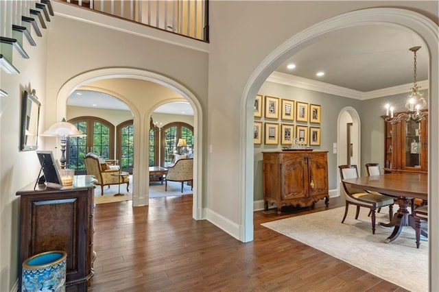 foyer with an inviting chandelier, ornamental molding, a towering ceiling, and dark hardwood / wood-style flooring