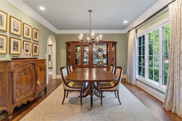 dining space featuring a notable chandelier, dark wood-type flooring, and ornamental molding