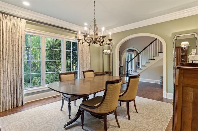 dining space with a notable chandelier, crown molding, and dark wood-type flooring