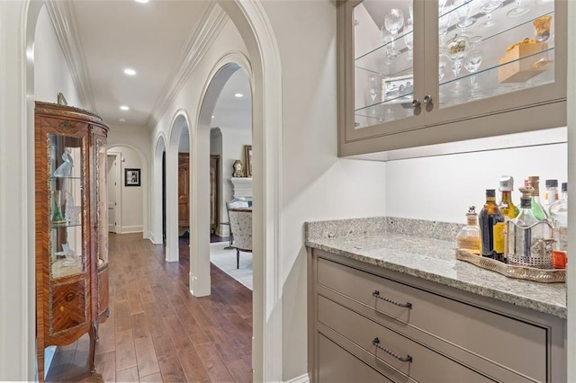 bar featuring crown molding, hardwood / wood-style floors, and light stone counters